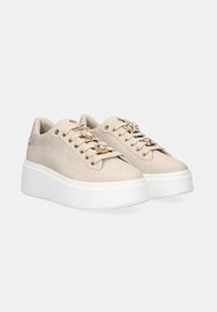 Zapatillas de plataforma beige de ante, con acentos decorativos en la parte superior, punta redondeada y suela de goma blanca.