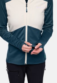 Fleece jack met een crèmekleurige, gequiltte bovenkant en donkergestreepte mouwen; heeft een rits aan de voorkant en duimgaten in de boorden voor een betere pasvorm.