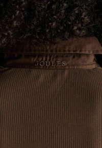 Brown ribbed fabric with a smooth texture; features embroidered "Joules" logo at the neckline. Simple design with no additional accents.