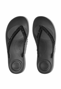 Zwarte slippers met een gestructureerde rubberen voetbed, voorzien van een gladde, gevormde zool en een versierde band met zwarte accenten.