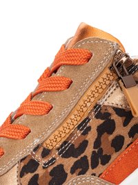 Close-up van een sneaker met oranje veters, beige suède, luipaardprintstof en een functionerende beige rits met metalen trekker.