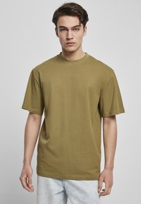 Tricou din bumbac de culoare verde măslin, cu guler rotund, mâneci scurte și o croială lejeră. Are un design simplu și o textură subtilă.