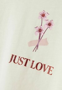 La tela blanca presenta un estampado floral con flores rosas y acentos burdeos, acompañado del texto "SOLO AMOR" en rojo brillante.