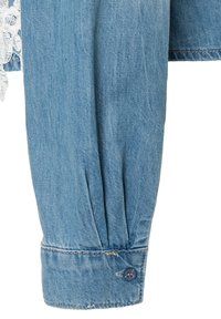 Light blue denim shirt sleeve with a buttoned cuff and visible white lace trim on the adjacent fabric.