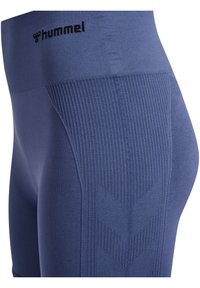 Marinblå leggings med ribbad textur, med chevronmönster längs sidorna och en svart logotyp vid midjan.