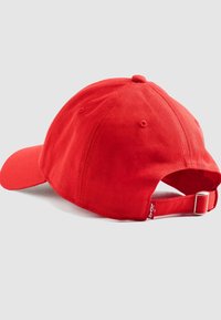 Rood katoenen baseballpet met een gebogen klep, verstelbare strap aan de achterkant en een klein logotaggertje aan de zijkant. Vloeiende textuur en klassiek ontwerp.