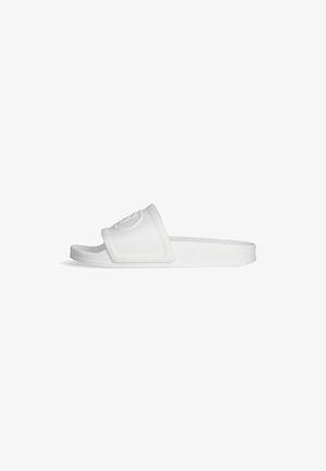 Valge liugjalats, millel on tekstureeritud rihm jõulise reljeefse logoga, lame talla ja minimalistlik disain.