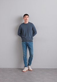 Gray long-sleeve sweatshirt, blue jeans, and white sneakers. Simple design, relaxed fit, smooth texture, and light colors.