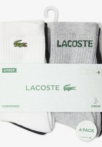 Six-pack crew socks in white and gray. Features ribbed texture, cushioned design, and embroidered green Lacoste logo on each sock.
