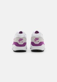 Kopačke Nike Air z belo mrežasto zgornjico, svetlo sivo sempljenko in vijolično peto s brandingom; črn podplat.