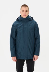 Giacca impermeabile blu navy con cappuccio, caratterizzata da una vestibilità dritta, chiusura con zip e due tasche laterali. Texture liscia e branding minimale.