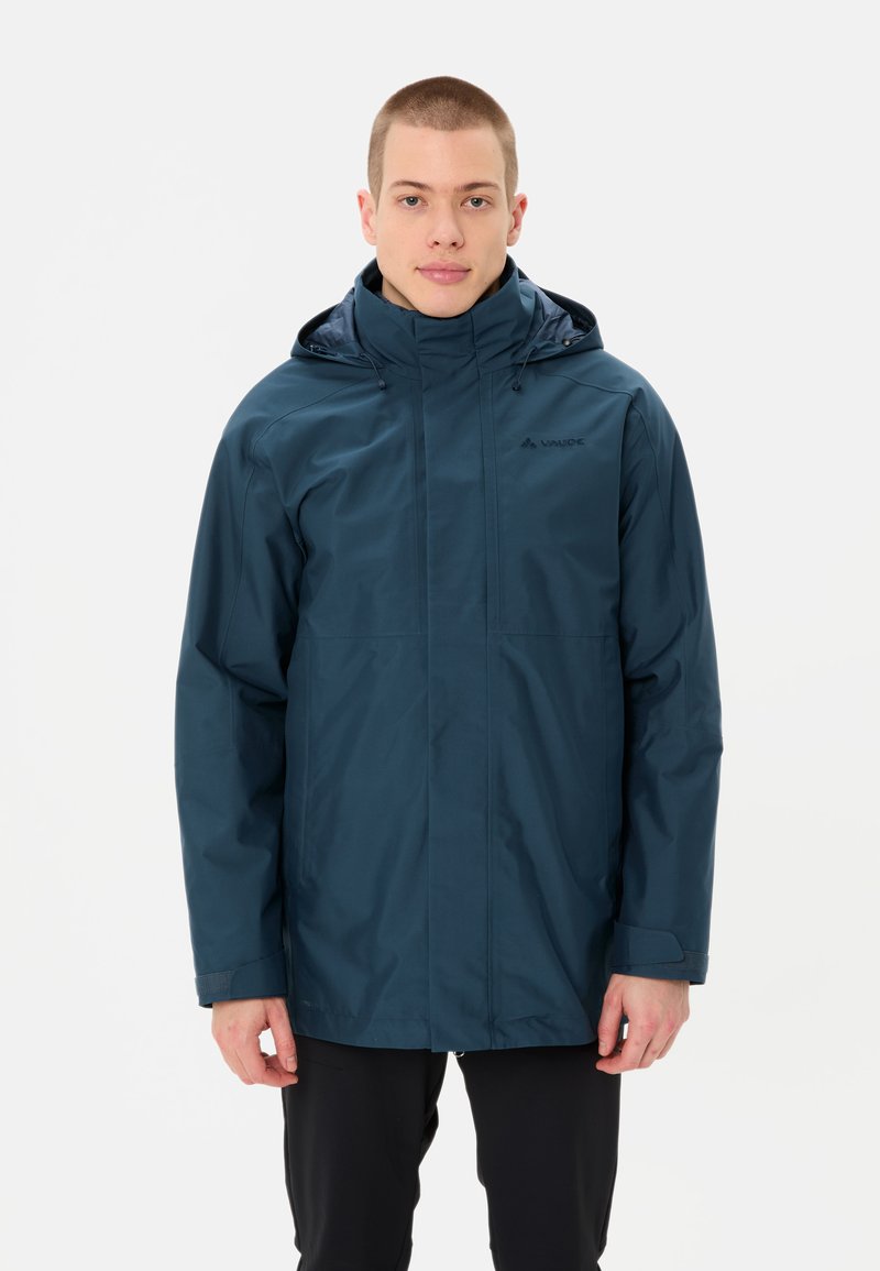 Giacca impermeabile blu navy con cappuccio, caratterizzata da una vestibilità dritta, chiusura con zip e due tasche laterali. Texture liscia e branding minimale.