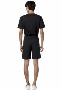 T-shirt nera e pantaloni corti abbinati, entrambi realizzati in tessuto leggero. La T-shirt presenta un design semplice; i pantaloni corti hanno un elastico in vita.