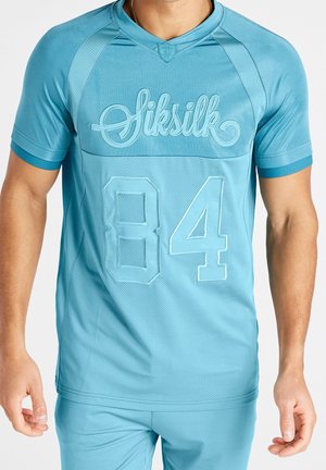 Maillot de sport bleu ciel en tissu respirant, présentant une texture en mesh, des manches courtes, et le numéro "84" en caractères gras avec le logo de la marque brodé.