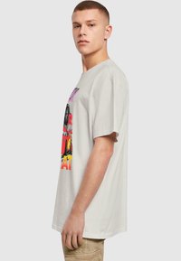 Lys grå bomulds T-shirt med korte ærmer, prydet med farverig grafisk tryk med tekst. Casual pasform, rund halsudskæring, blød tekstur.