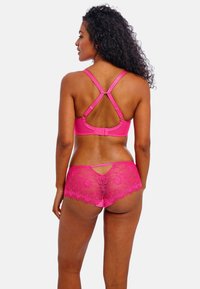 Ensemble de lingerie rose comprenant un bralette rembourré avec des bretelles réglables et un dos en dentelle florale, associé à une culotte assortie avec des bordures en dentelle.