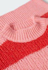 Col de pull en maille douce avec texture côtelée en rose, présentant une large bande horizontale rouge sur le tissu.