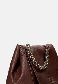 Borsa a mano in pelle marrone con una finitura texture. Presenta una tracolla a catena intrecciata e un accento con logo sul davanti.