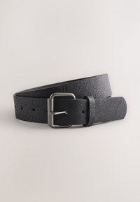Ceinture en cuir noir texturé avec boucle rectangulaire en métal argenté, enroulée sur un fond gris clair.