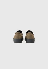 Pantofi maro din suede cu talpică din cauciuc negru, având o formă elegantă și rotunjită, cu detalii minime de coasere pe partea superioară.