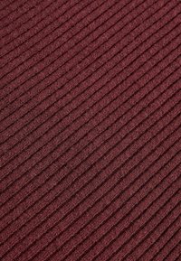 Rippstoff in tiefem Burgunderrot, mit einer sanften Textur und gleichmäßig verteilten vertikalen Linien. Das Material wirkt warm und gemütlich.
