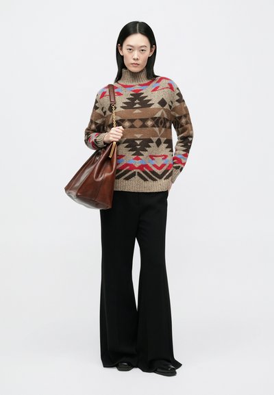 Strikket sweater i brun med geometriske mønstre i rød, blå og sort, kombineret med sorte udvidede bukser og en brun lædertaske.
