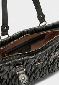 Borsa a tracolla nera in pelle con texture trapuntata, dotata di chiusura con zip, finiture color oro e interno marrone con una piccola tasca.