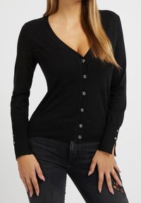 Black cardigan with a deep V-neck, button-down front, ribbed cuffs, and decorative buttons. Soft fabric with a fitted design.