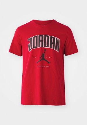 Rød bomulds T-shirt med sort "JORDAN" tekst og en silhuetgrafik af en springende figur med en basketball. Korte ærmer, rund hals.