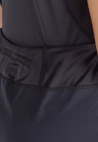 Zwarte sportkleding met een getailleerd ontwerp. Kenmerkt zich door een gestructureerd mesh-paneel en een ritszak op de tailleband voor extra gemak.