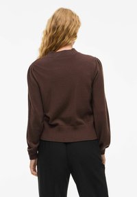 Brązowy sweter wykonany na drutach, z okrągłym dekoltem, bufiastymi rękawami i ściągaczem na dole. Miękka tekstura i dopasowany krój, prezentujący widok z tyłu.
