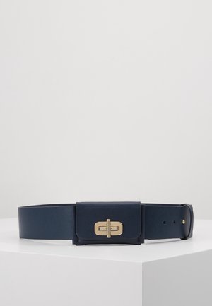Ceinture large bleu marine avec petite pochette attachée présentant un fermoir à tour rectangulaire doré, exposée sur une surface blanche.
