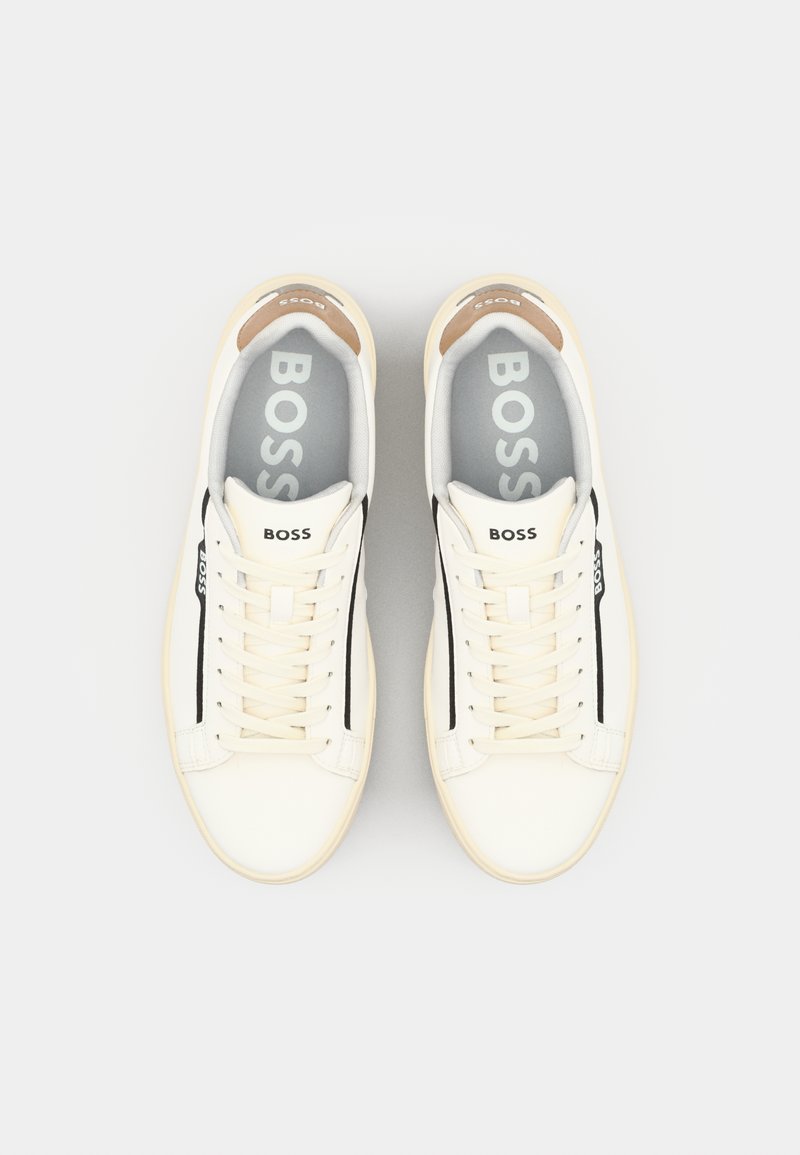 Baskets en cuir blanc avec des accents beiges, des rayures noires et des semelles intérieures grises. Dotées de lacets traditionnels et d'un design de talon arrondi.