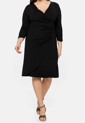 Schwarzes Kleid mit V-Ausschnitt und dreiviertellangen Ärmeln. Mit gerafften Details an der Seite und einem taillierten Bund. Glatter Stoff.