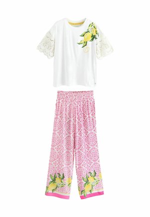 Hvid kortærmet T-shirt med blonde detaljer og citrusskrift; lyserøde mønstrede bukser med blomstermotiver og citron grafik forneden.