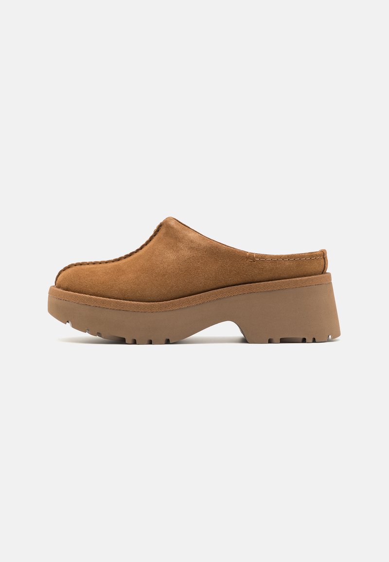 Zoccoli in suede beige con punta rotonda e dettagli cuciti, dotati di una spessa suola in piattaforma marrone con presa texture.
