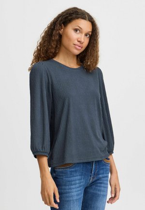 Dunkelgrauer, gerippter Pullover mit Dreiviertelärmeln, rundem Ausschnitt und lockerer Passform, kombiniert mit blauen Jeans.
