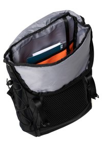 Sac à dos avec une coque extérieure noire et une doublure grise, comportant des poches latérales en mesh et une fermeture roll-top. Contient des cahiers de différentes couleurs.