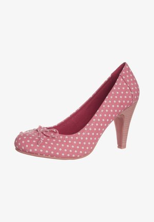 Różowe buty na wysokim obcasie w białe kropki, zaokrąglony nosek, mała kokardka z przodu i pięta na stosie.