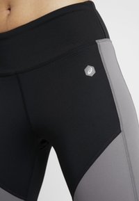 Leggings a vita alta con un design a blocchi di colore nero e grigio, realizzati in materiale elastico con una texture liscia e dettaglio del logo.