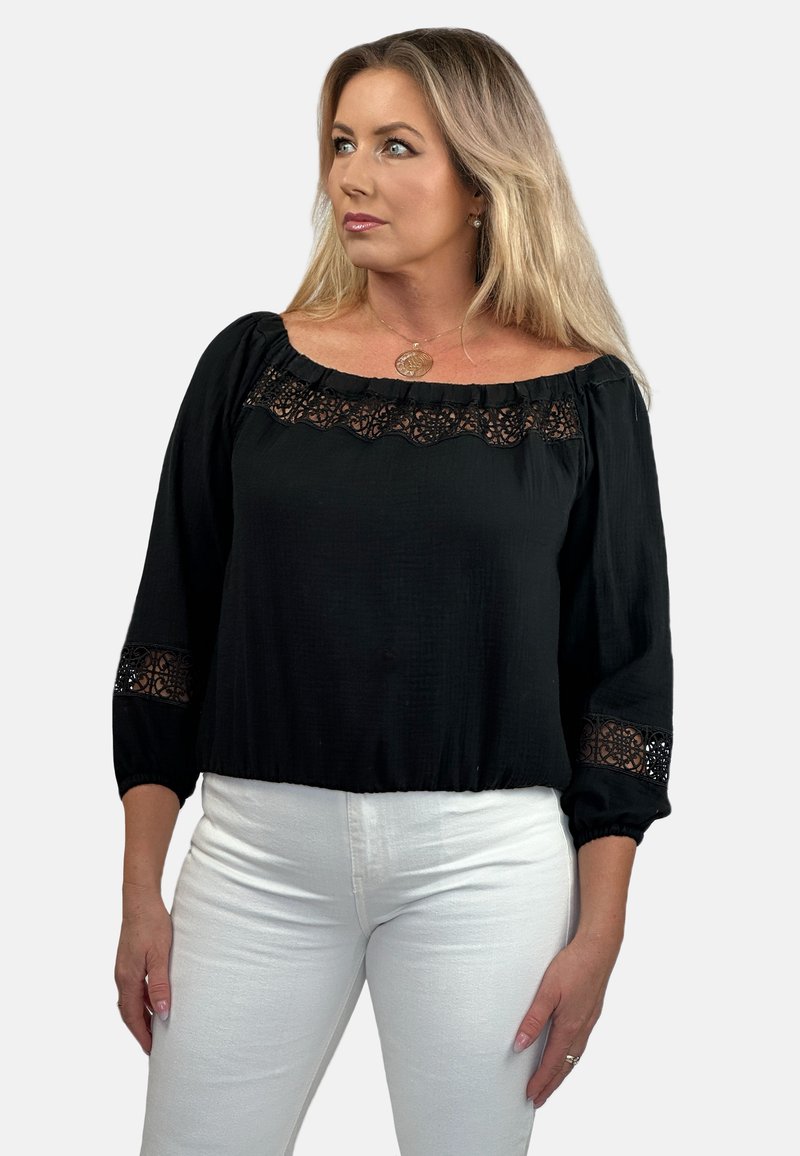 Czarna bluzka z fasonem odsłaniającym ramiona, z koronkowymi detalami przy dekolcie i rękawach. Wykonana z lekkiego materiału.