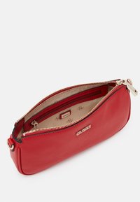 Bolso de cuero rojo con cremallera dorada, forma ovalada y bolsillo interior. Presenta un logo embossado y textura suave. Vista abierta.