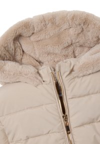 Giacca imbottita beige con cappuccio foderato in morbido pelo sintetico, zip dorata e dettagli cuciti sul corpo. Il tessuto strutturato aggiunge calore.