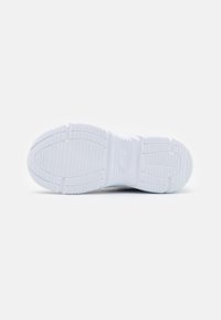 Semelle de sneaker blanche avec des motifs de grip texturés et la marque Skechers, vue du dessous sur un fond blanc uni.