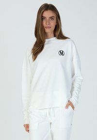 Weißes Sweatshirt mit lockerer Passform, langen Ärmeln und Rundhalsausschnitt. Verfügt über ein kleines schwarzes Logo auf der Brust. Glatte Textur.