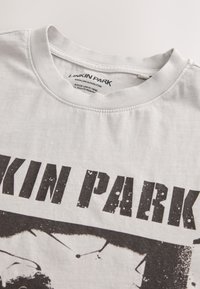 Maglietta grigia in cotone con scollo rotondo, decorata con una grafica nera stampata con la scritta "Linkin Park" e una texture consumata nelle lettere.