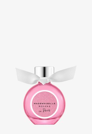 Round pink perfume bottle with silver cap and white ribbon tied around neck, labeled "Mademoiselle Rochas in Paris."