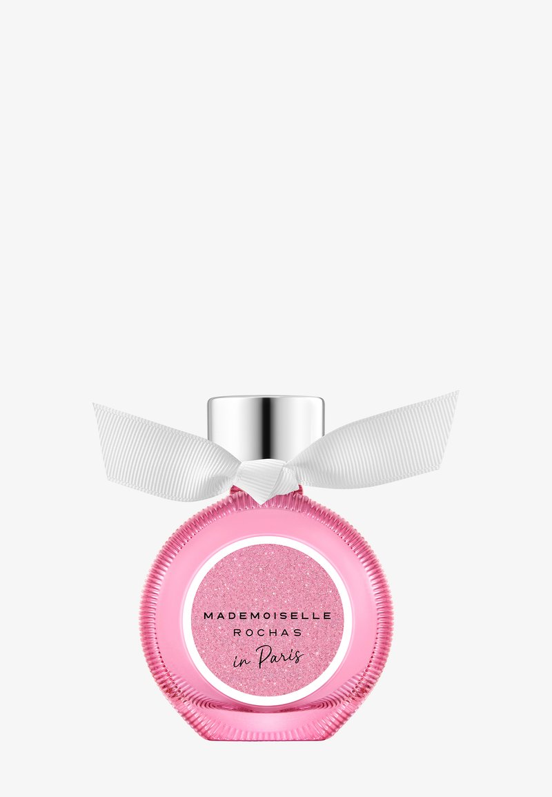 Flacon de parfum rond rose avec bouchon argenté et ruban blanc noué autour du col, étiqueté « Mademoiselle Rochas à Paris. »