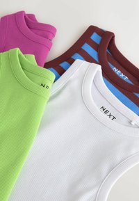Quatre débardeurs côtelés pliés en violet, vert lime, blanc et rayures bleu-marron, étalés à plat avec les encolures visibles.