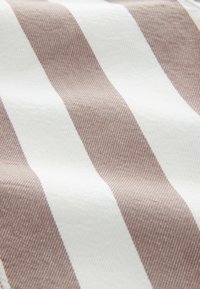 Textil mit abwechselnden braunen und weißen Streifen; der Stoff hat eine glatte Textur und eine strukturierte Webart, die klare visuelle Linien erzeugt.